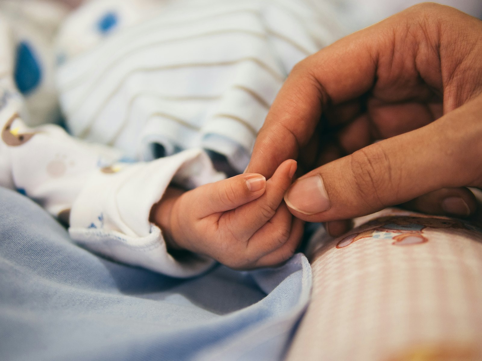 Mano de un adulto sosteniendo la mano de un bebé
